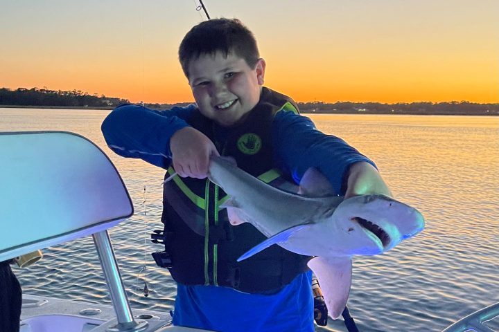 a young boy holding a fish in the water